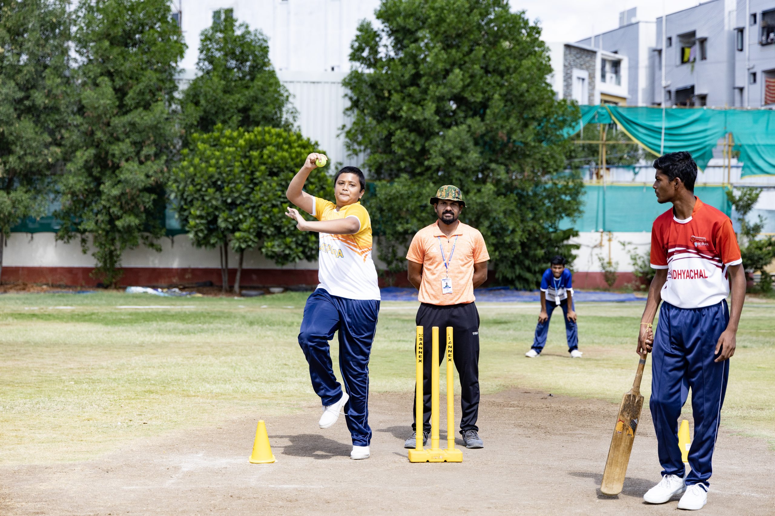 Energetic students actively engaged in a friendly game of cricket at Kiran International School, demonstrating teamwork and sporting spirit on a sunny day.