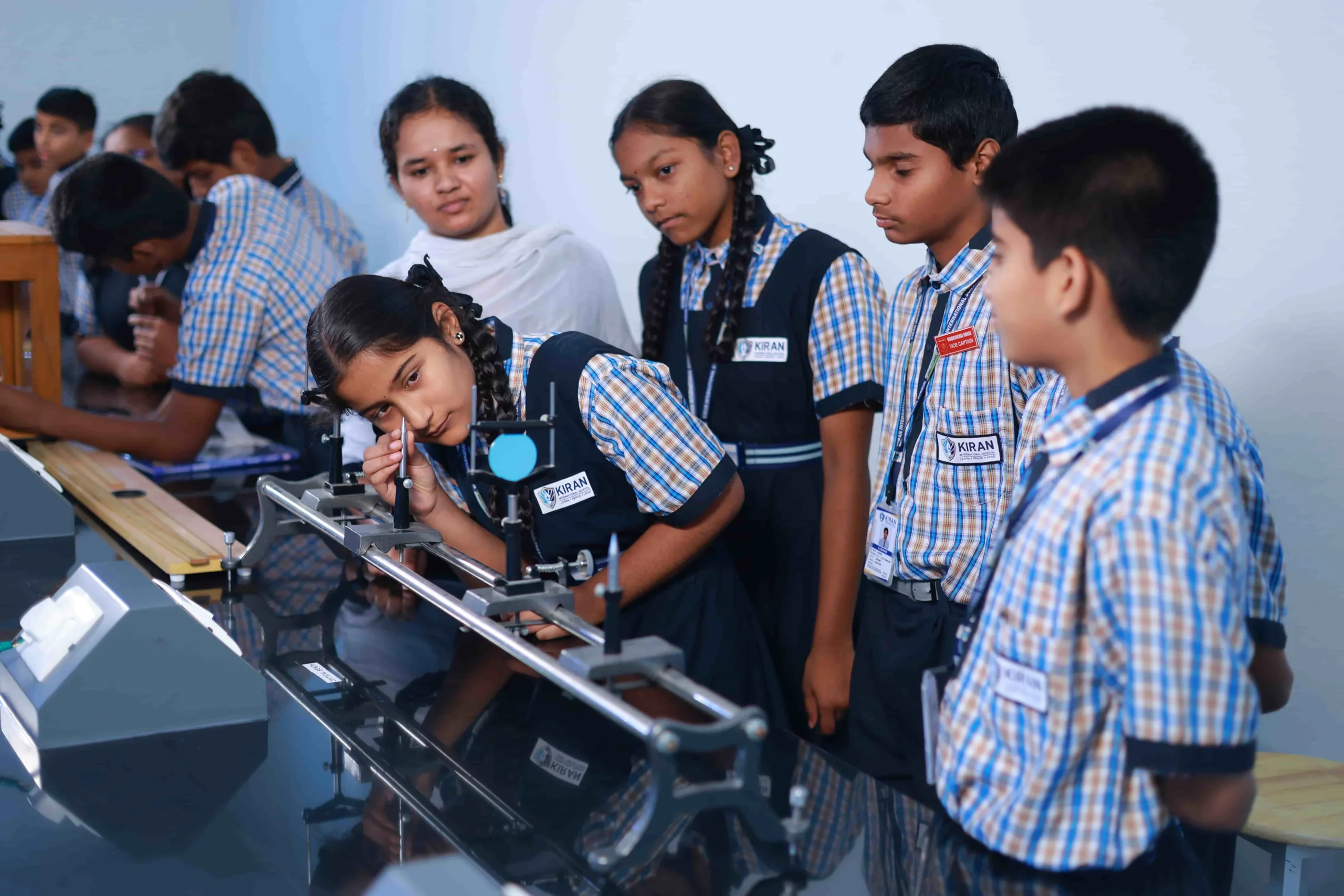 Students engaged in a science practical session under the supervision of a teacher at Kiran International School, fostering hands-on learning and scientific exploration.