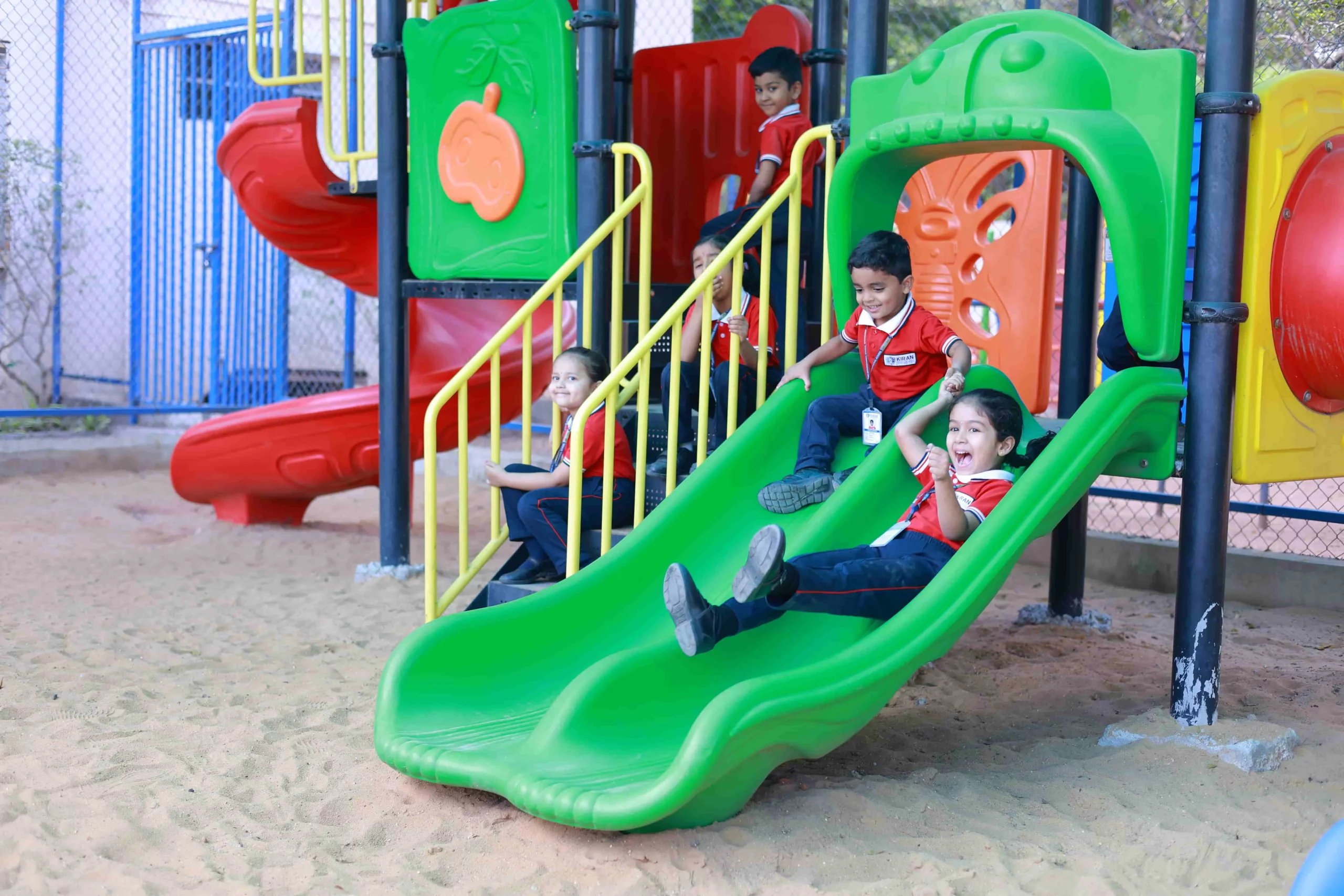 Joyful students actively enjoying a multi-play station set in a sandpit at Kiran International School, experiencing fun and camaraderie through play and exploration.